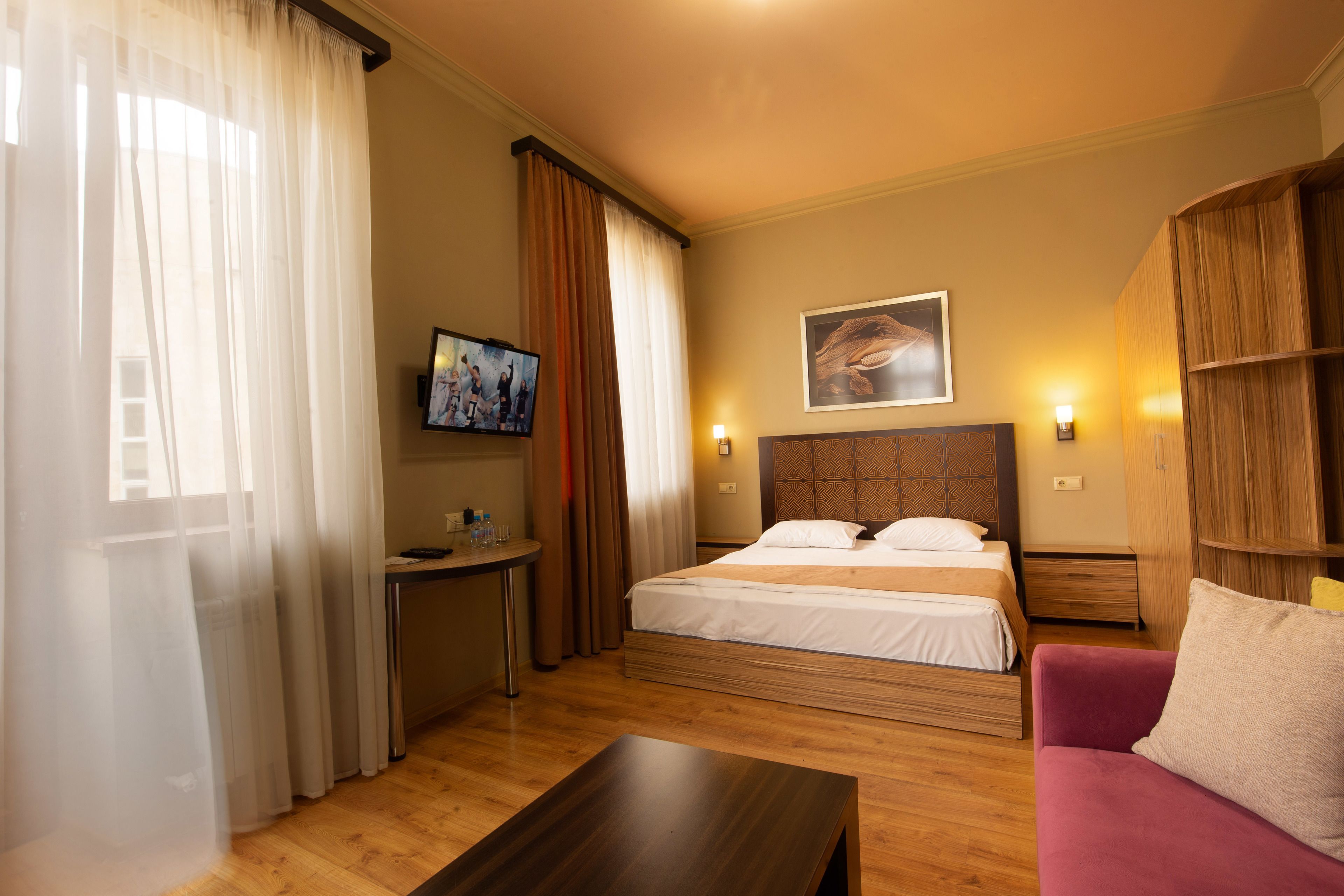 Une chambre d’hôtel avec un lit, un bureau, une télévision et un canapé.
