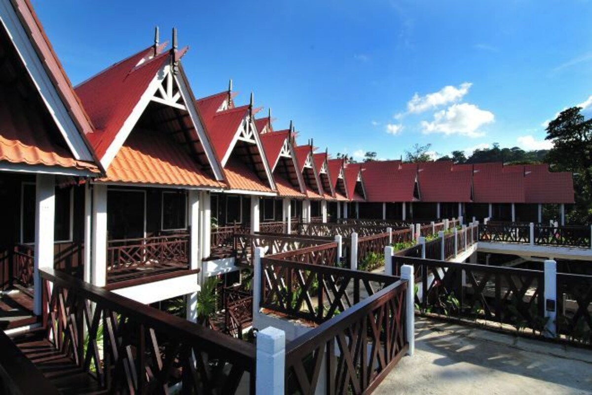 A row of hotel rooms with red roofs and white trim, connected by a covered walkway.