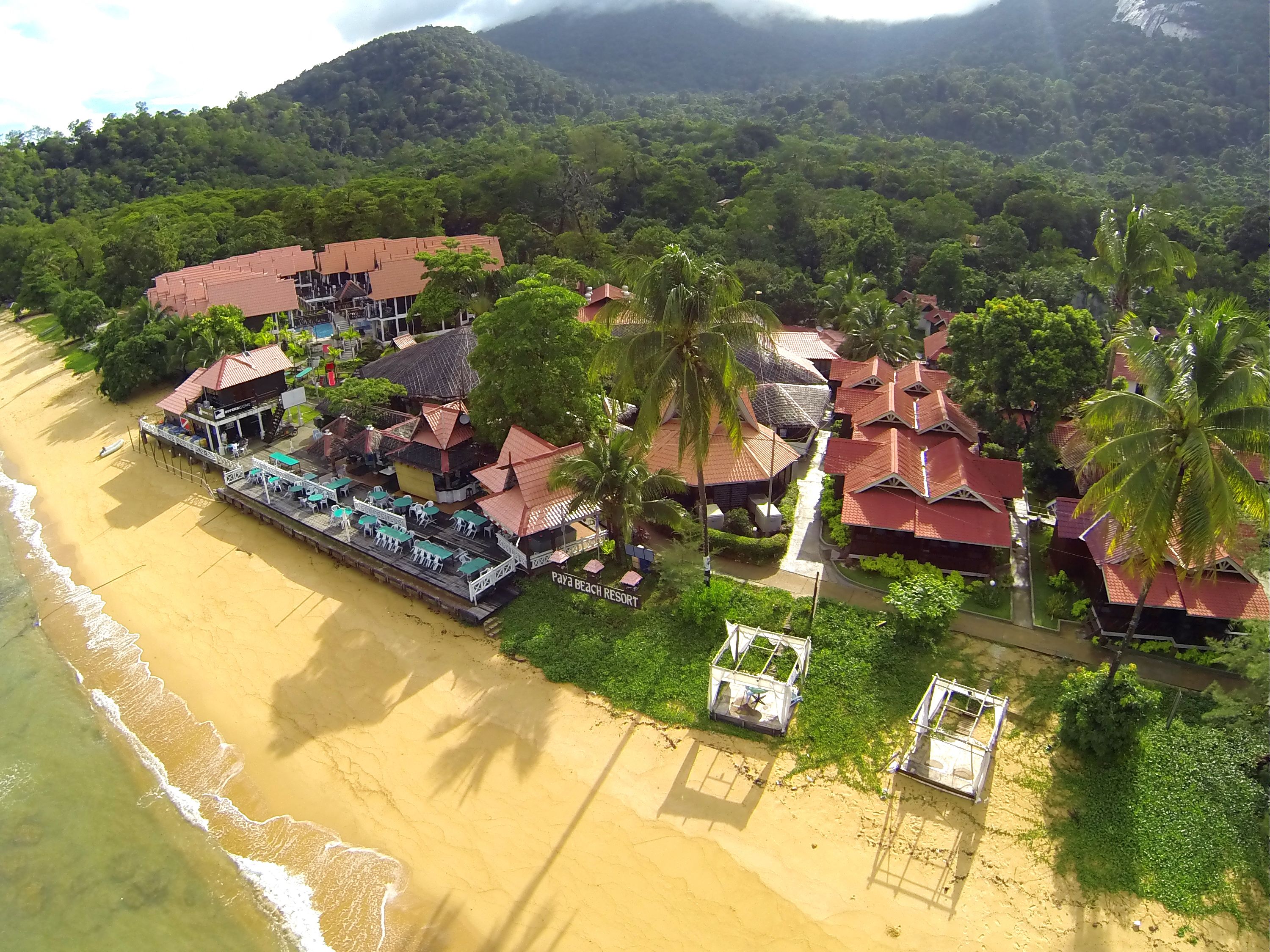 Um resort com acesso à praia, vários edifícios e palmeiras.