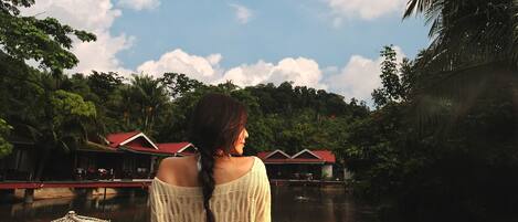 A person sitting on a wooden dock overlooking a body of water with houses in the background.