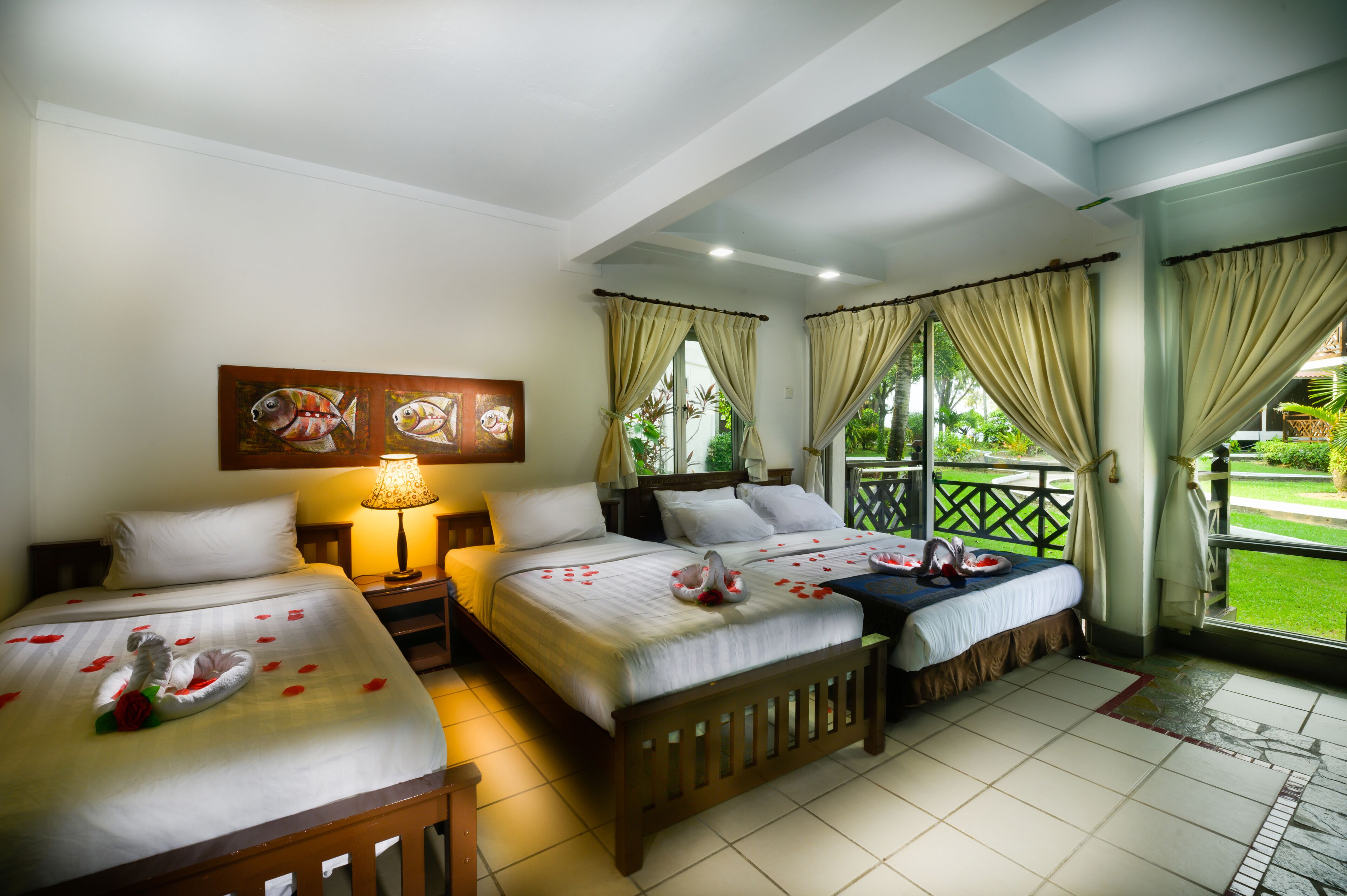 A hotel room with two beds, a nightstand, a lamp, and a window with curtains.