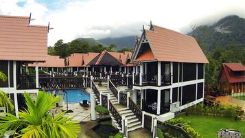 Stroll through lush gardens to a tranquil pool area, surrounded by majestic mountains.