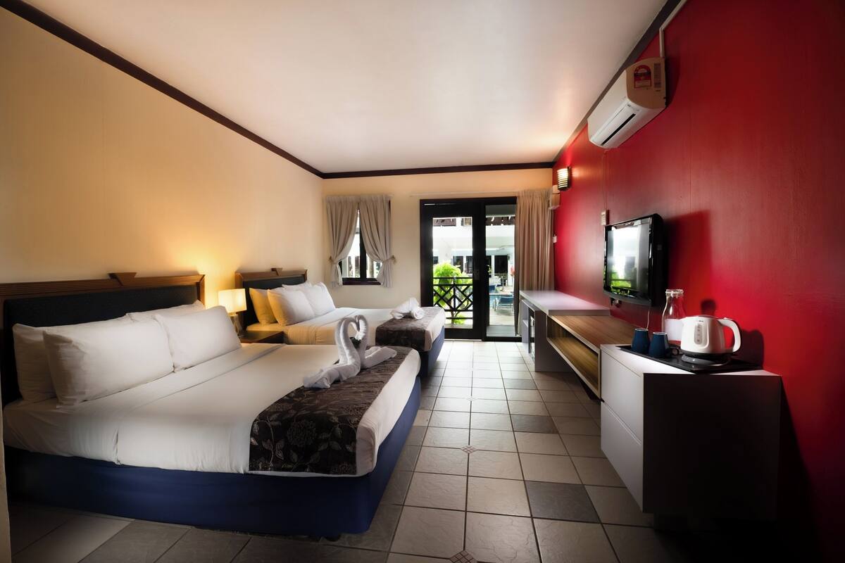 Ein Hotelzimmer mit Bett, Schreibtisch, Fernseher und einer Küchenzeile.