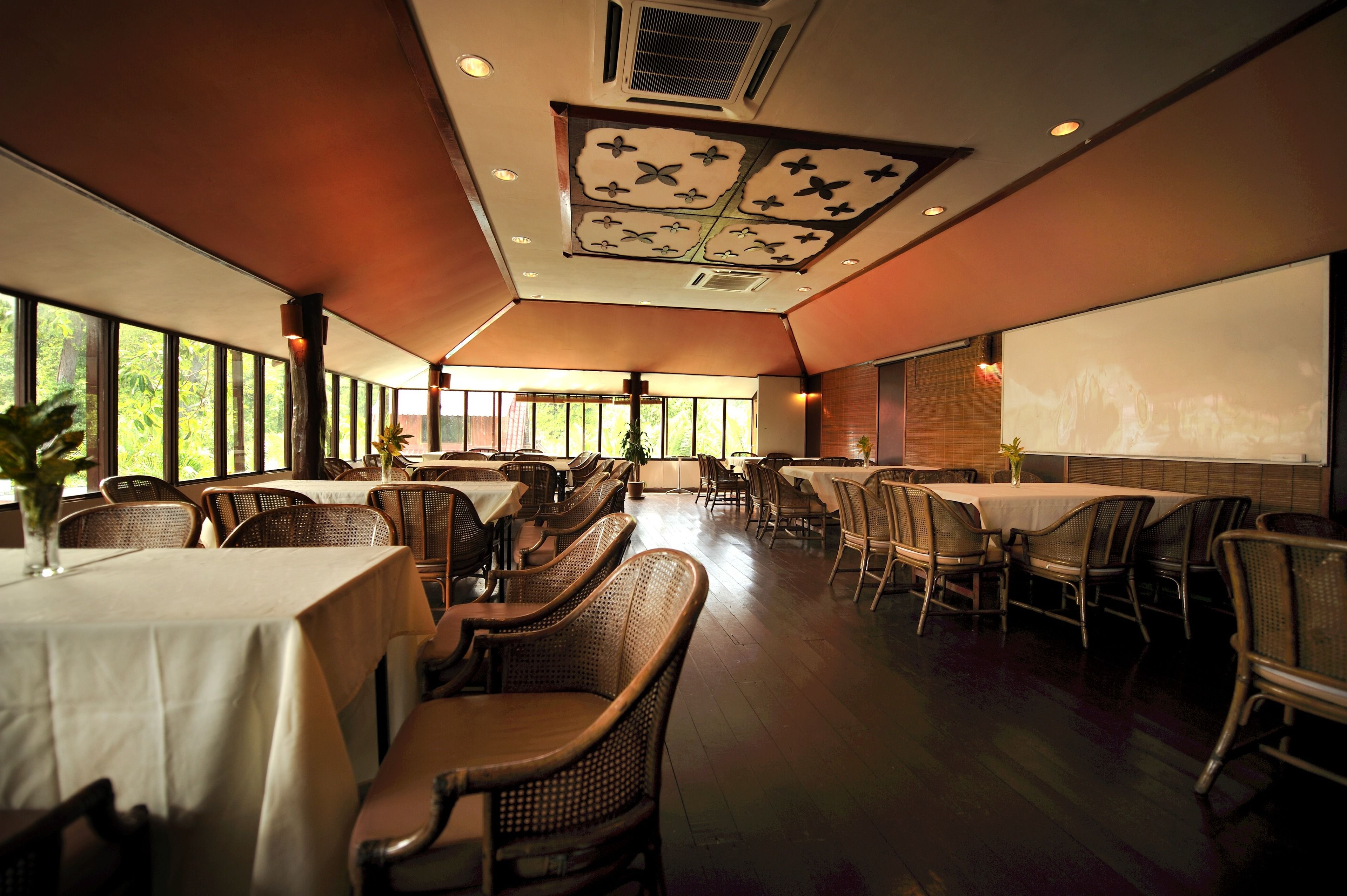 A spacious dining area with high ceilings, large windows, and a projector screen on the wall.