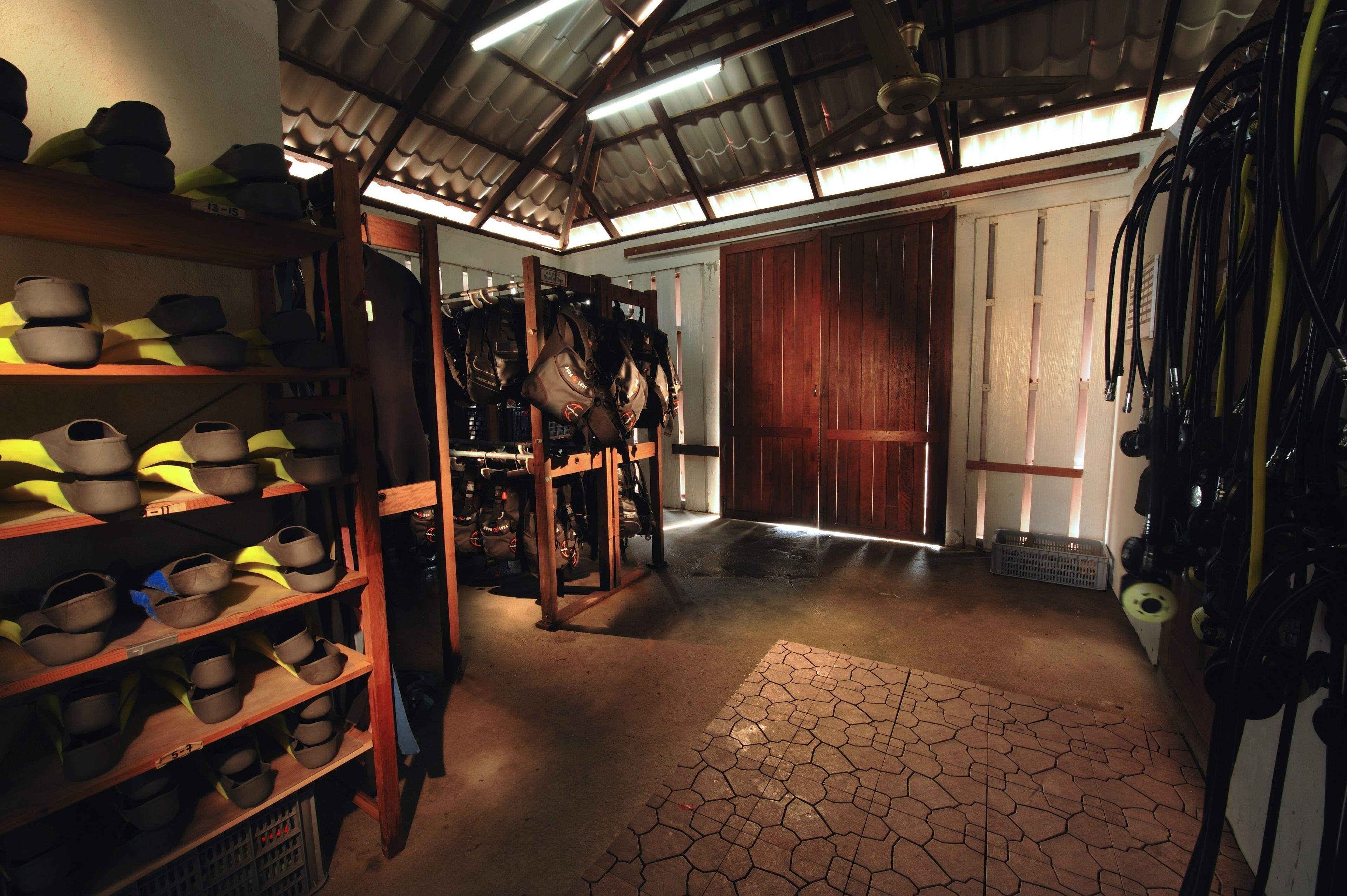 A storage area with shelves of shoes and bags, a wooden door, and a tiled floor.