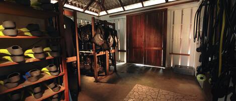 A storage area with shelves of shoes and bags, a wooden door, and a tiled floor.