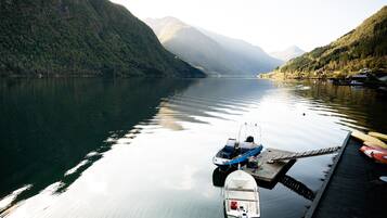 Un lago tranquillo con barche ormeggiate a un molo di legno, circondato da colline ricoperte di boschi.