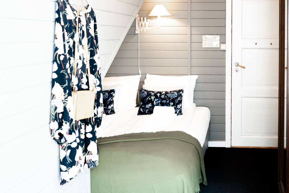 Ein Schlafzimmer mit Bett, einer Pendelleuchte, einer Tür und einem Gegenstand an der Wand.