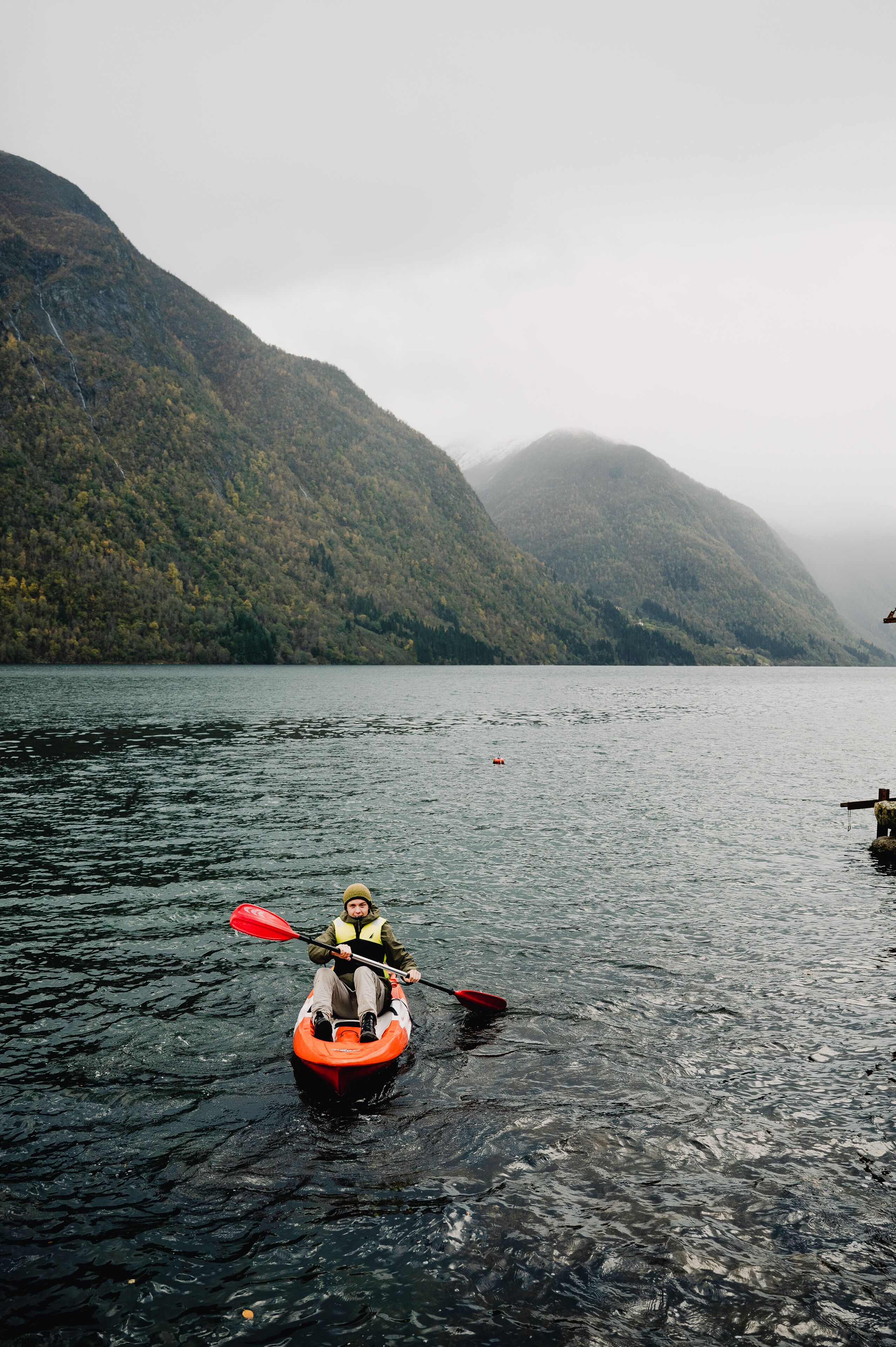 A kayaker on a calm lake with mountains in the background.
