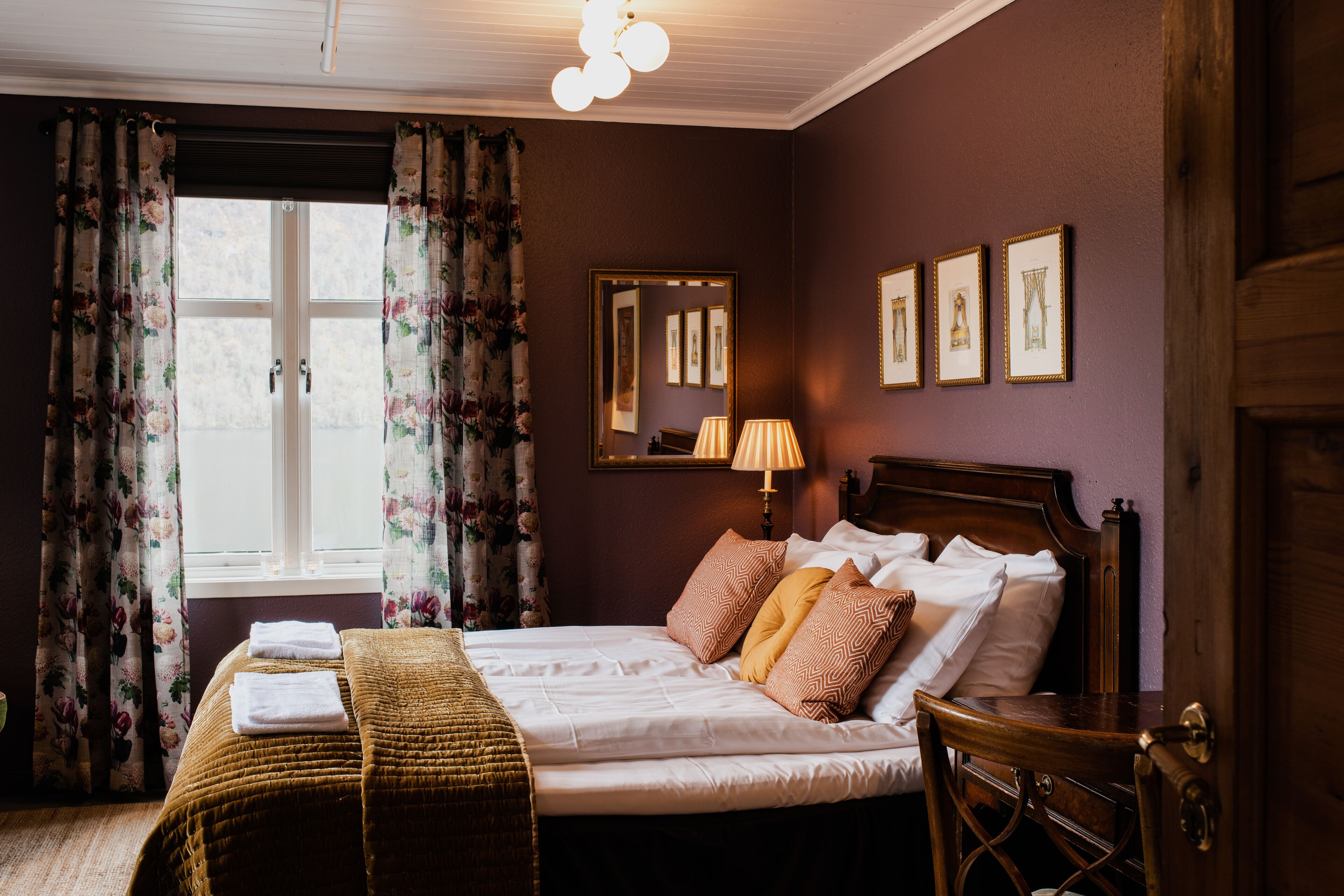 A neatly made bed with pillows, a bedside lamp, and a mirror on the wall.