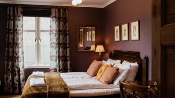 A neatly made bed with pillows, a bedside lamp, and a mirror on the wall.