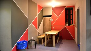 A small, modern room with a wooden table and benches, a trash bin, and a door with a 'DANGER' sign. - Zorbas Hotel - Hostel (Athens)