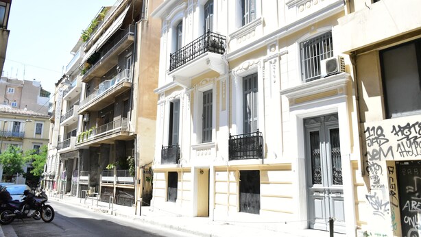A multi-story building with balconies, a motorbike parked on the street, and a building with graffiti. - Zorbas Hotel - Hostel (Athens)