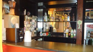 A bar area with stools, shelves of bottles, and a refrigerator. - Zorbas Hotel - Hostel (Athens)