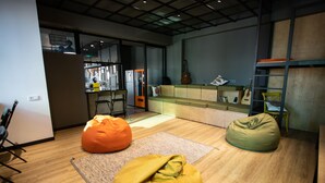 Un espacio de estar moderno con un sofá, sillones de felpa, una guitarra y una zona de cocina.