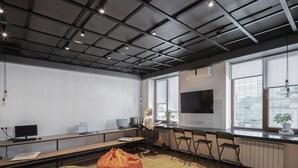 Un espacio de oficina moderno con una mesa grande, varias sillas, un sofá y un televisor en la pared.