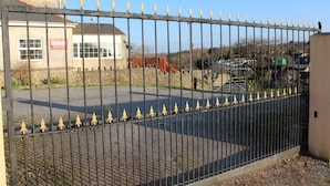 A gated area with a building in the background, a red bridge, and a clear sky. - The Middlegate Hotel (Pembroke)