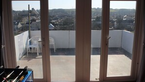 A balcony with a view of a residential area, a white plastic chair, and a foosball table. - The Middlegate Hotel (Pembroke)