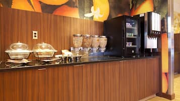A buffet area with a wooden counter, food dispensers, and a refrigerator.