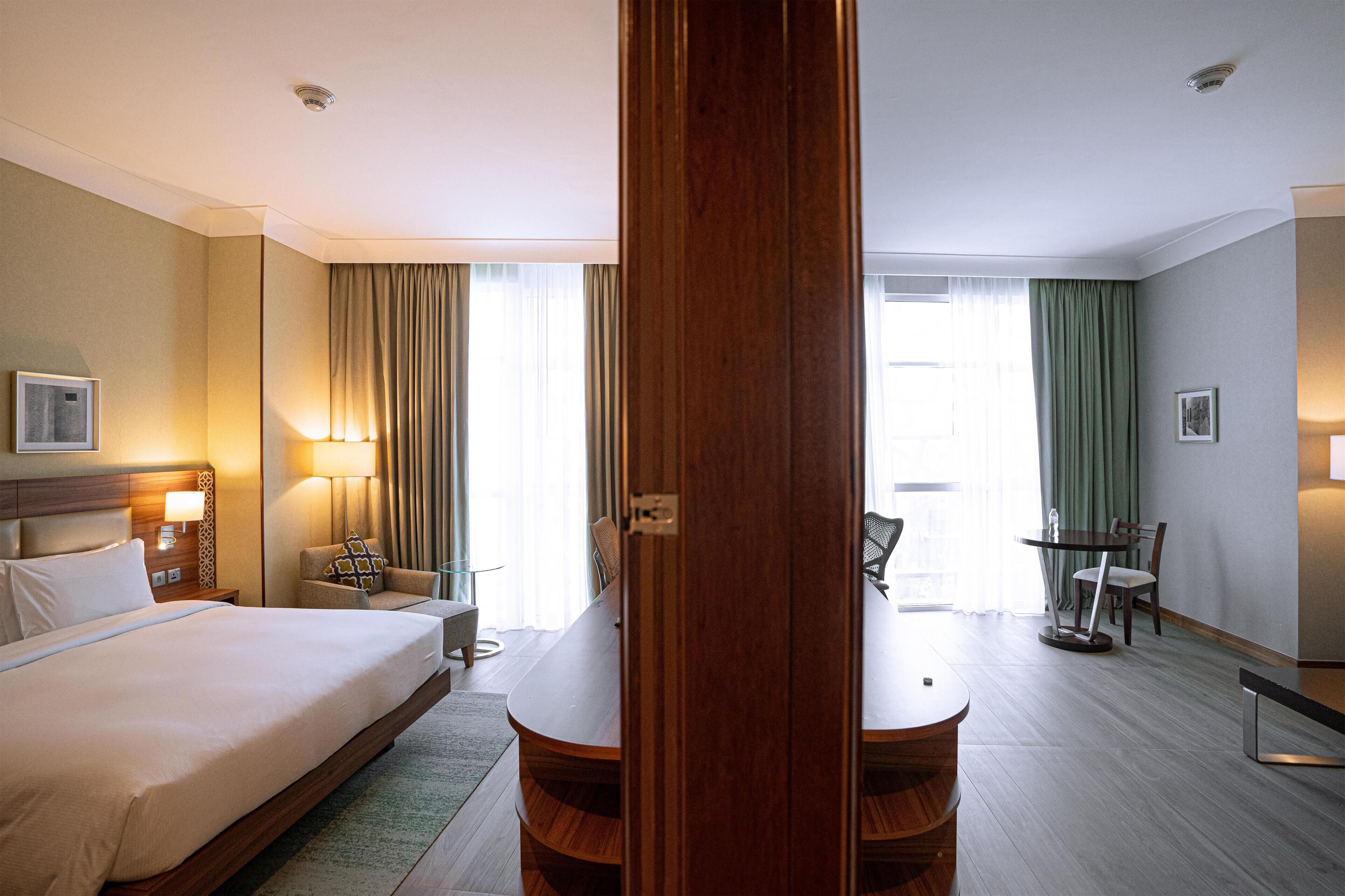 Een hotelkamer met een groot bed, een bureau, een stoel en een eettafel.