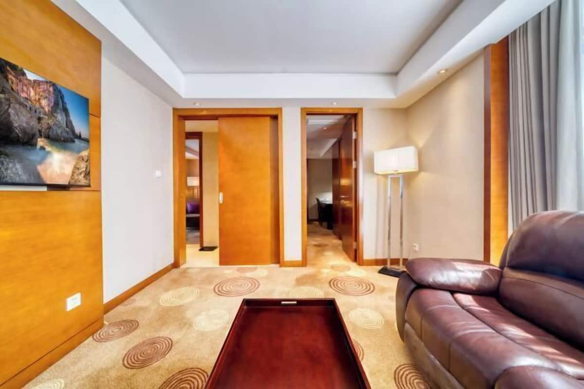 Een hotelkamer met een leren bank, een houten bijzettafeltje, een schilderij aan de muur en een lamp.