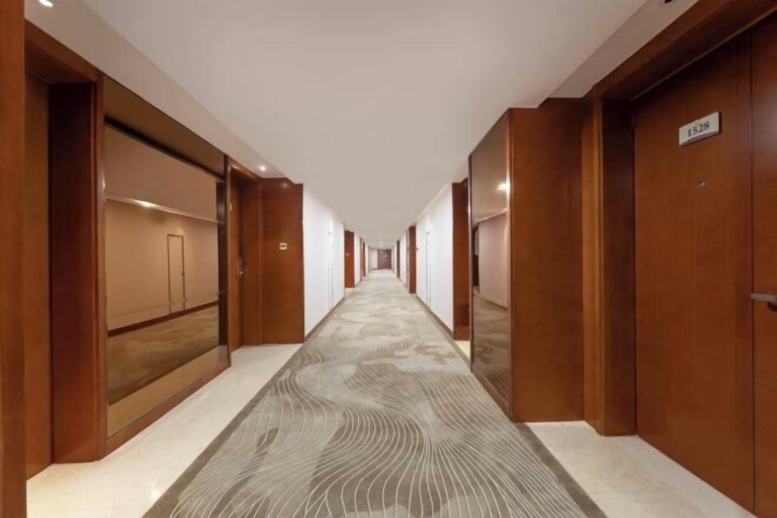 A long, narrow hallway with wooden doors on both sides and a patterned carpet.