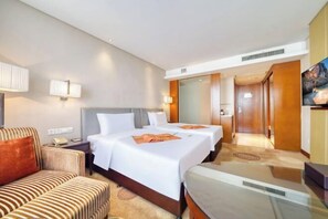 Une chambre d’hôtel avec deux lits, un canapé, un bureau et une télévision.