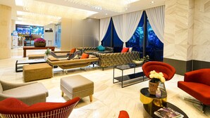 Eine moderne Lobby mit Sitzgelegenheit, einem Kronleuchter und Blick nach außen.