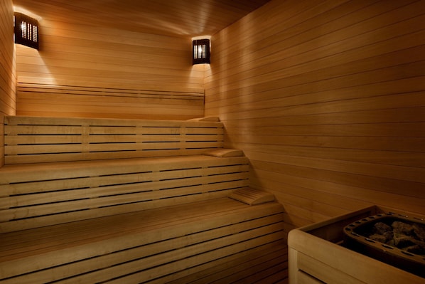 A wooden sauna with benches and a central heating element.