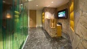 Un hall d’entrée avec un comptoir de réception, un téléviseur fixé au mur et une cloison en verre.
