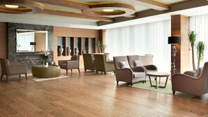 Un hall d’entrée spacieux avec une cheminée, des sièges confortables et un design moderne au niveau du plafond.