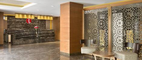 A lobby with a reception desk, seating area, and decorative panels.