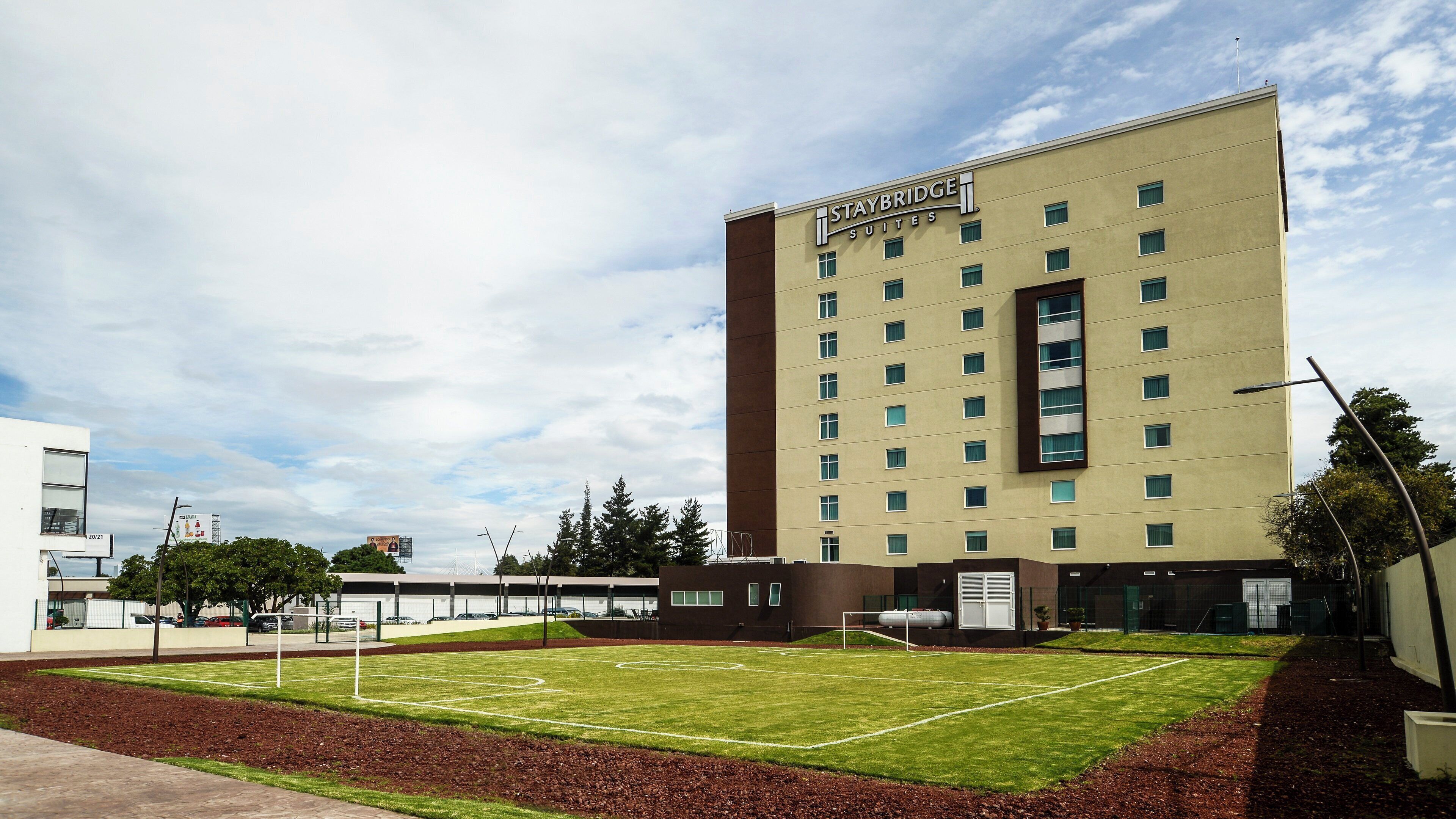 A hotel with a flat roof, multiple windows, and a sign reading 'STAYBRIDGE SUITES.'