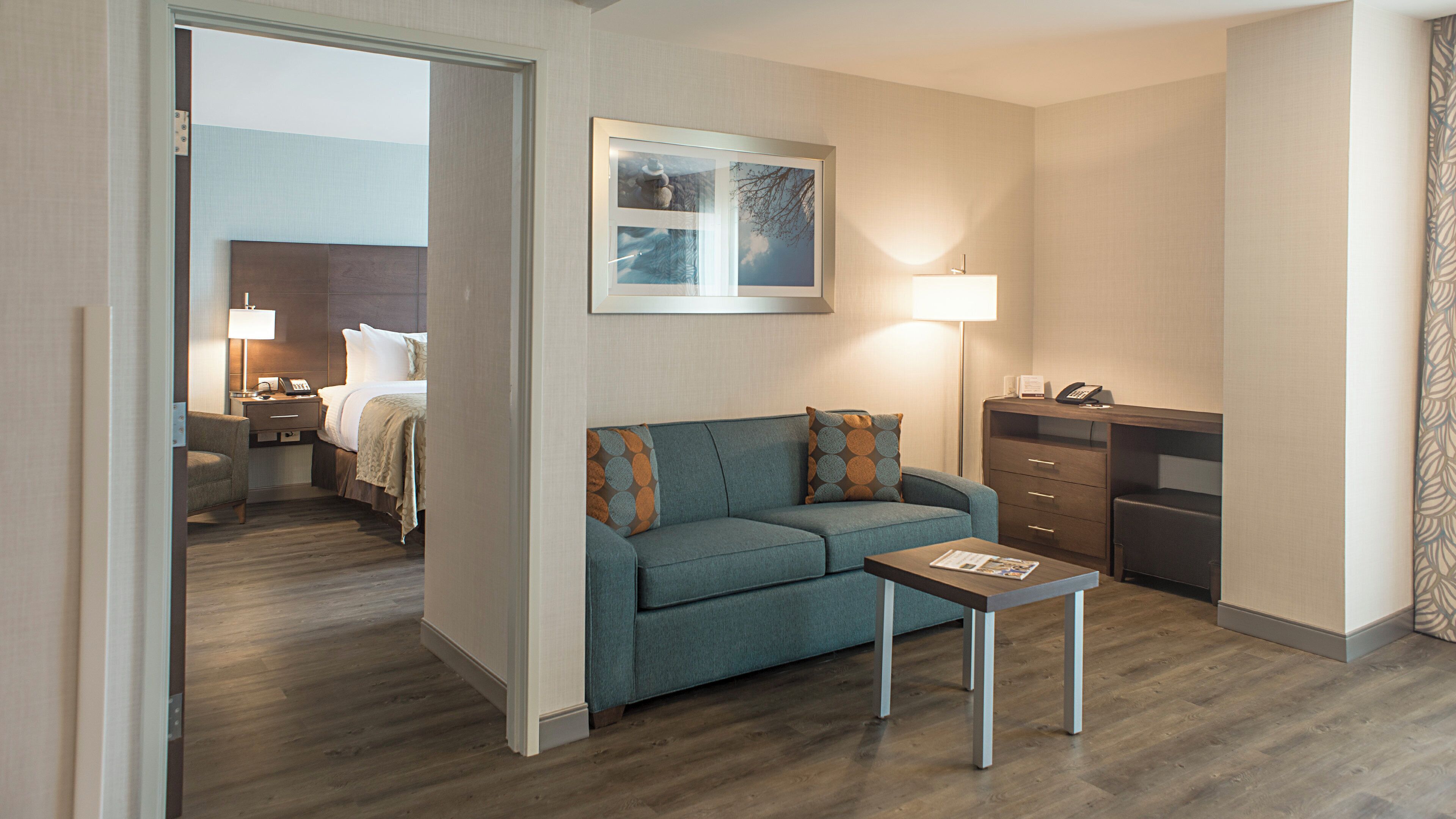 A hotel room with a bed, a sofa, a desk, and a small table.