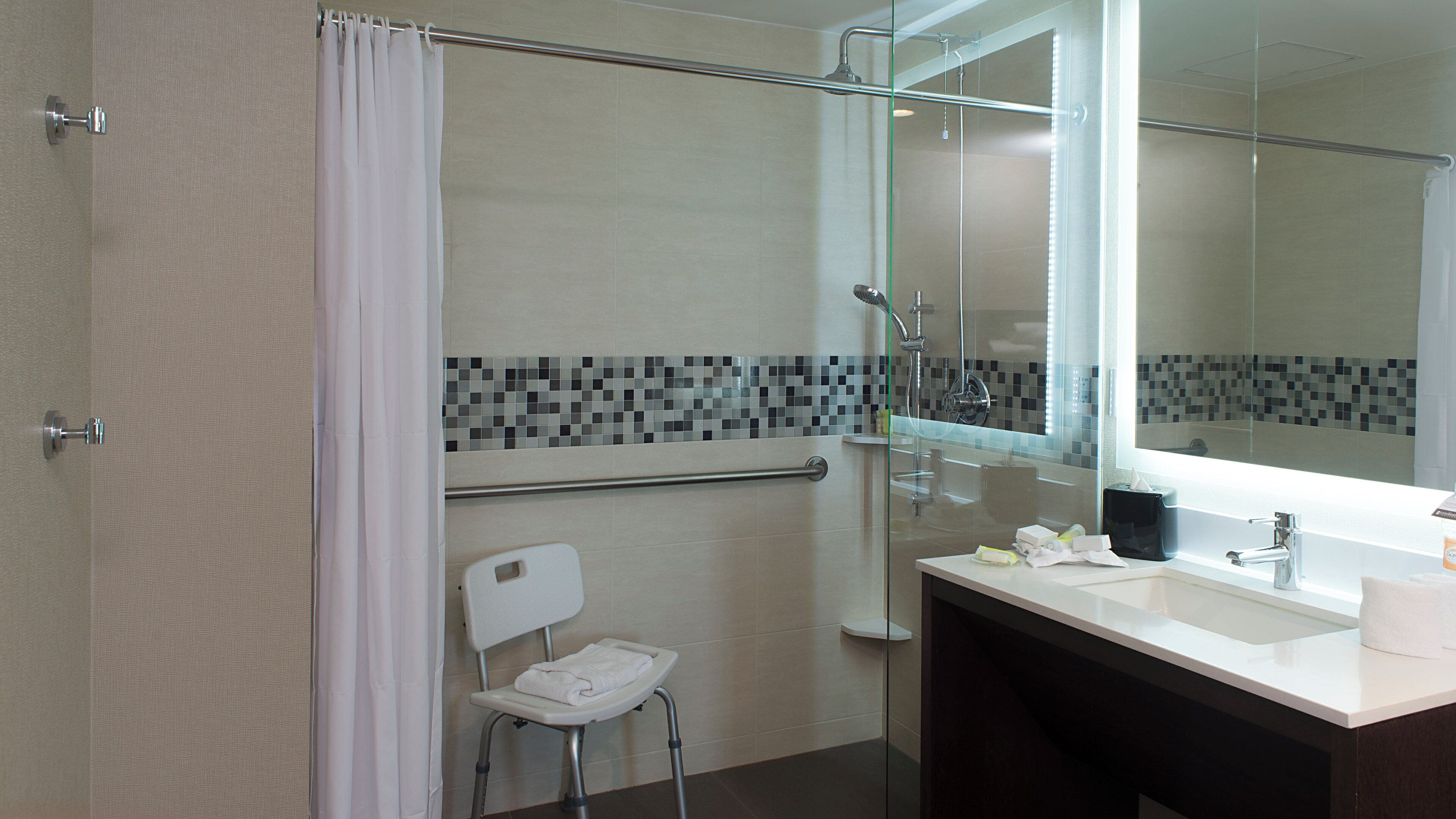 A modern bathroom with a glass shower enclosure, a white sink, and a mirror.