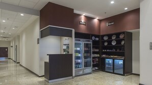 Un pasillo con BridgeMart y The Pantry, que cuenta con dispensadores de bebidas refrigeradas y una variedad de snacks y productos de panadería.