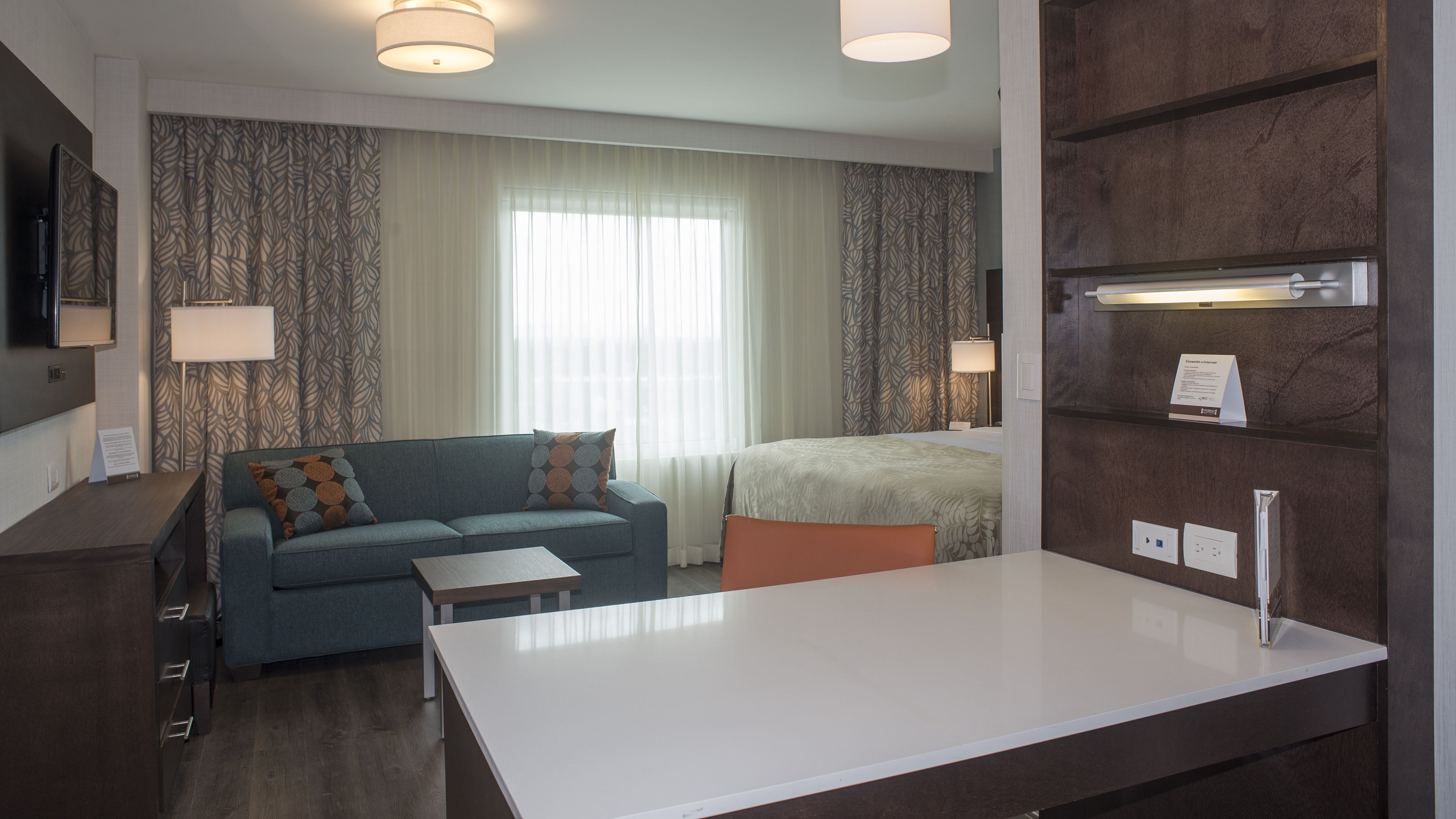Een hotelkamer met een bank, een bed, een bureau en een minibar.