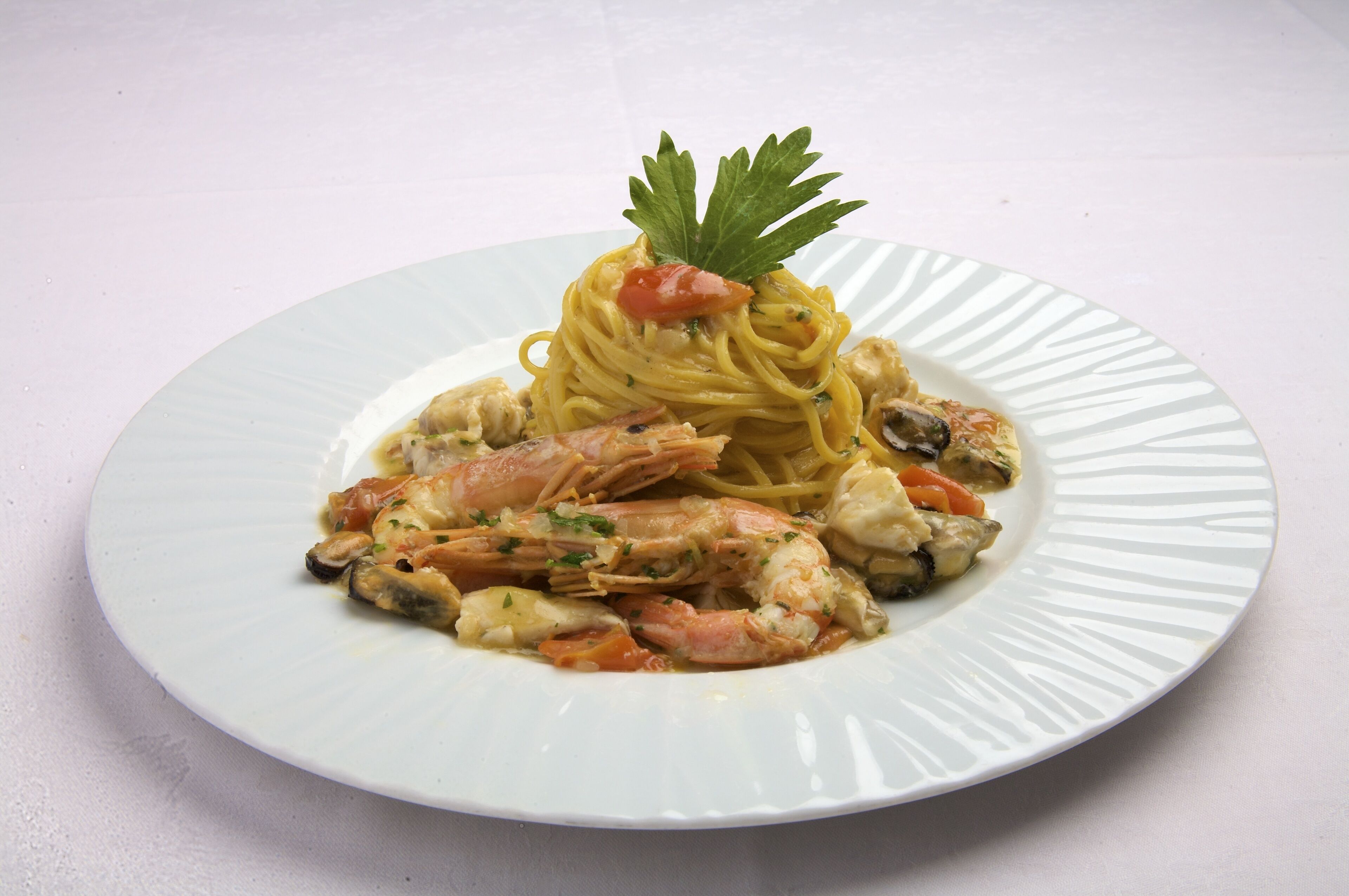 Un plato de espagueti con camarones y mejillones, adornado con perejil.