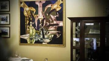 Un cuadro colgado en una pared de una habitación con una mesa y sillas.
