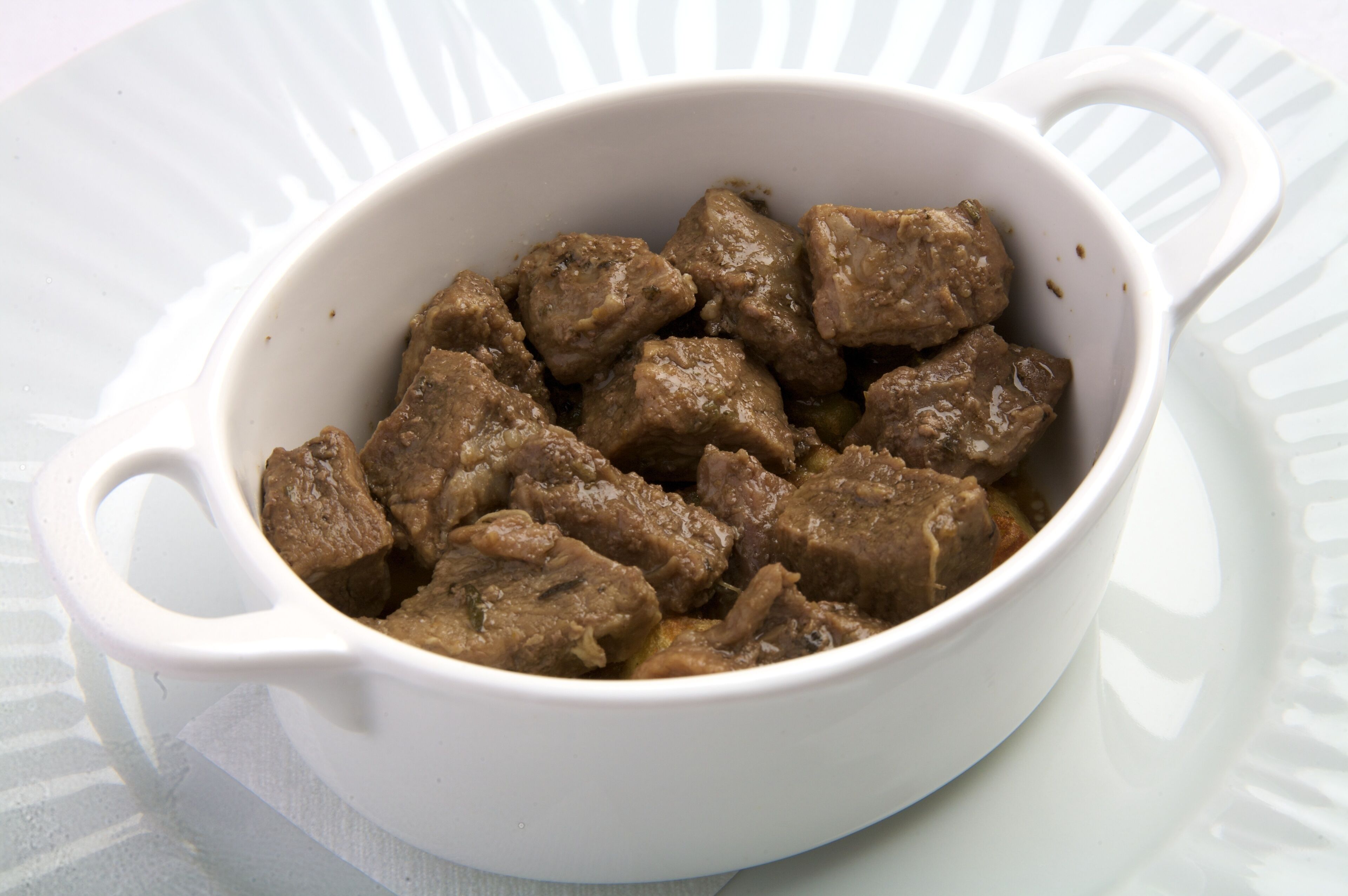 Un bol en céramique blanche contenant des morceaux de viande cuite.