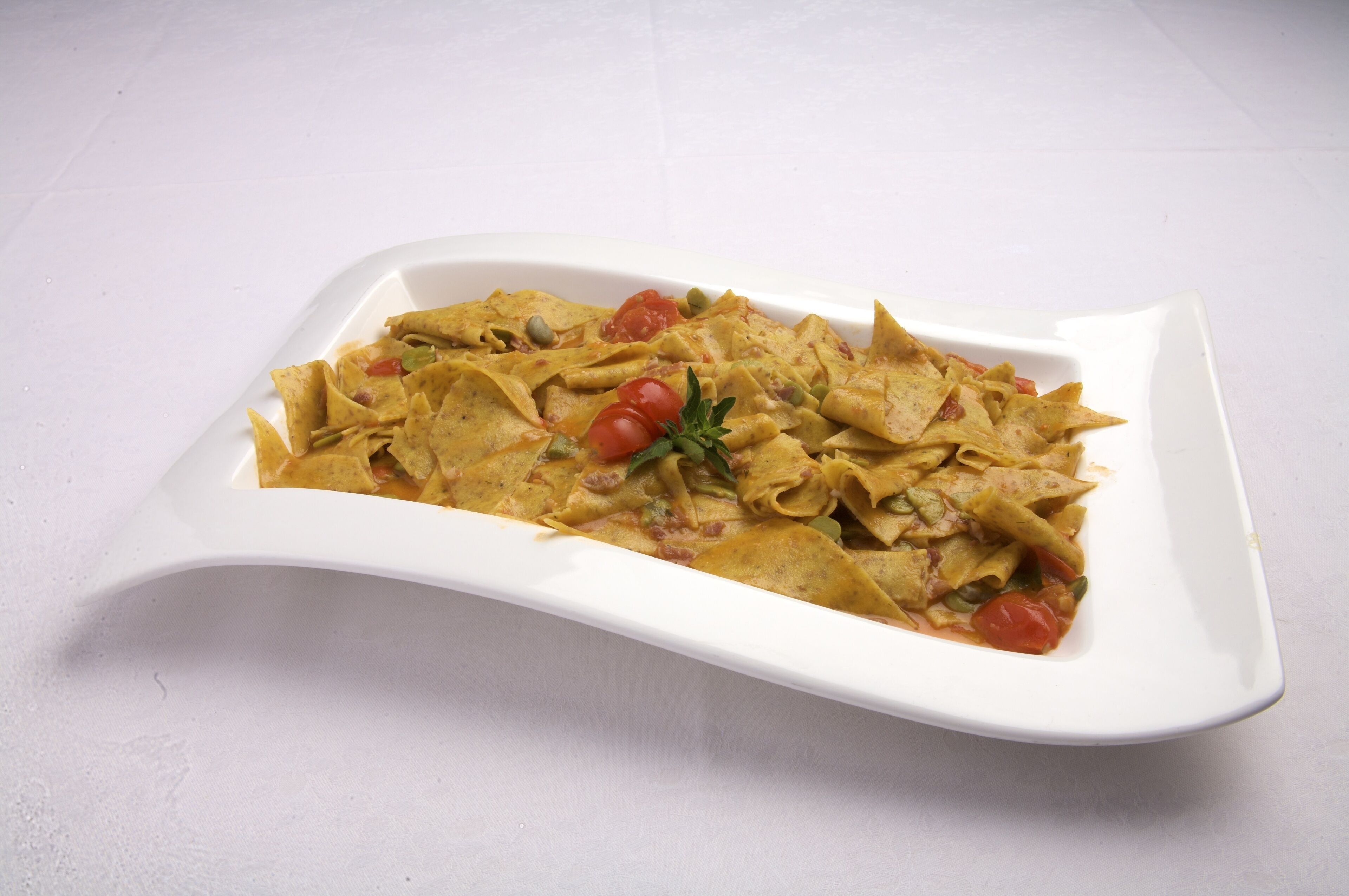 A white rectangular plate with a dish of tortilla strips and vegetables.