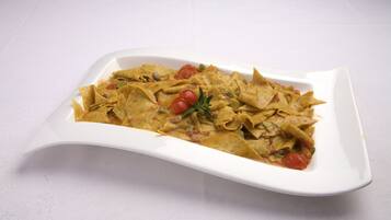 A white rectangular plate with a dish of tortilla strips and vegetables.