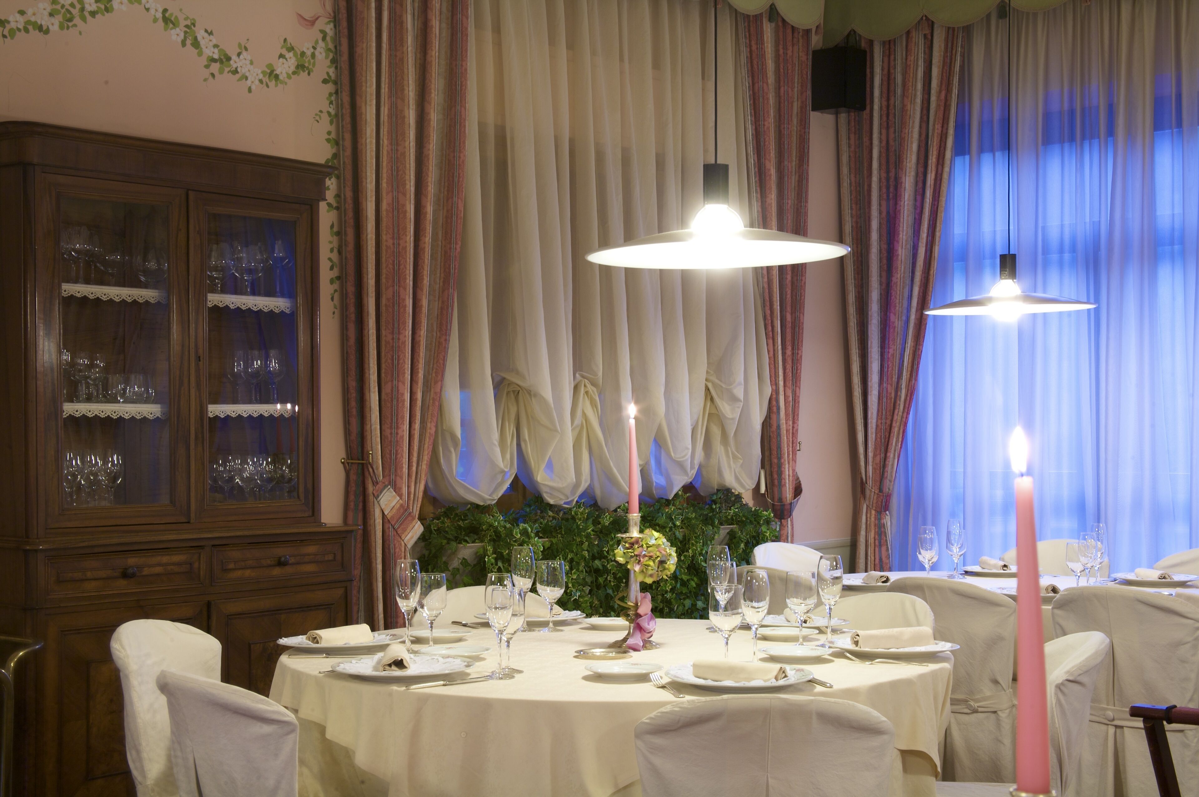 A dining area with round tables, white tablecloths, and candles.