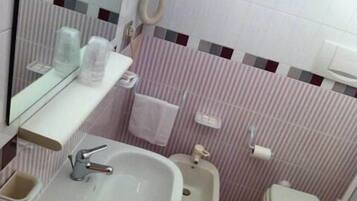 A small bathroom with a sink, a bidet, and a toilet.