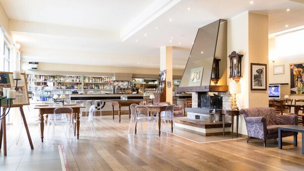 A spacious hotel lobby with a bar area, wooden flooring, and clear chairs. - Hotel Giardino (San Lorenzo in Campo)