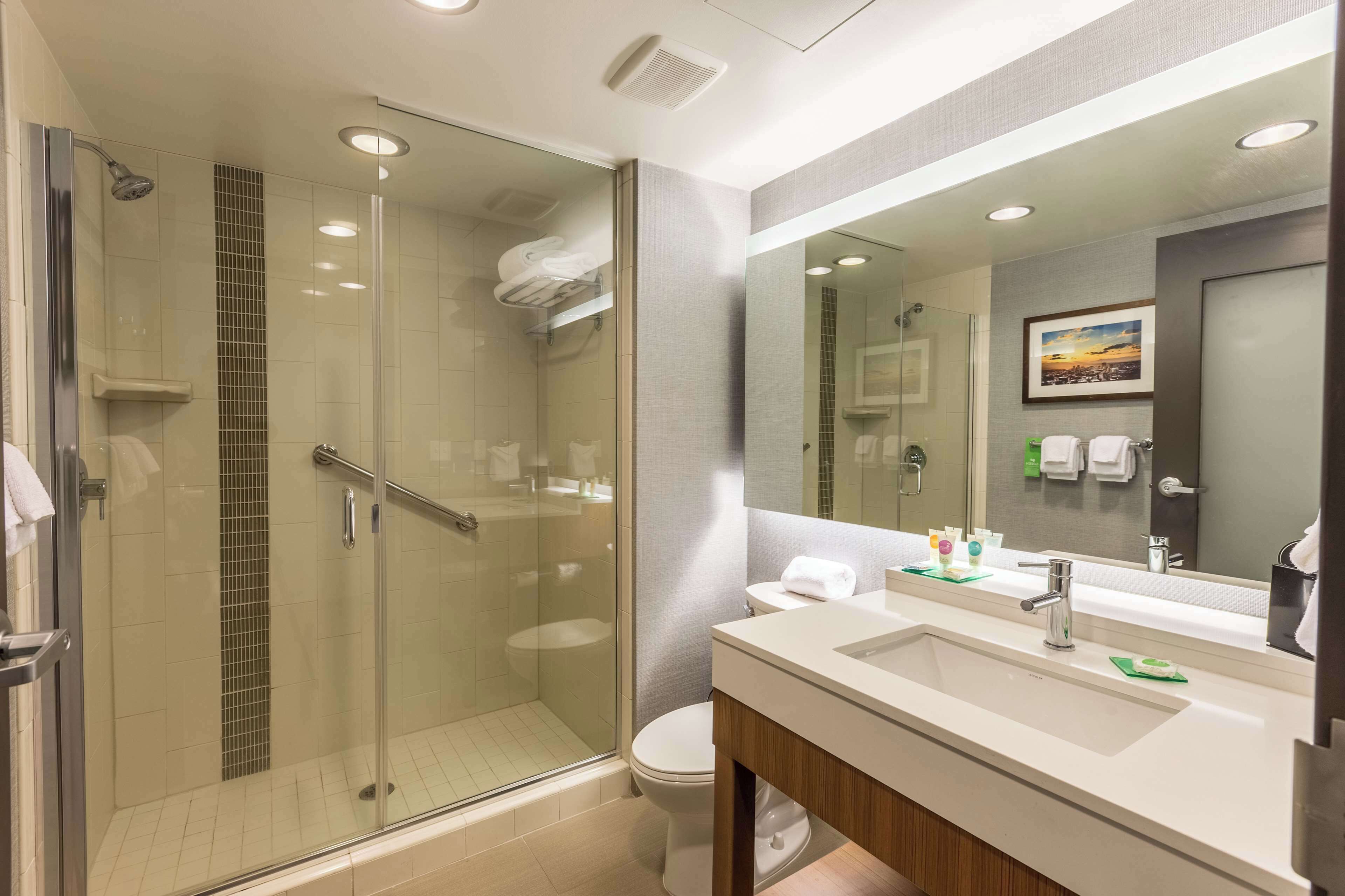 A modern bathroom with a glass-enclosed shower, a large mirror, and a sink with a vanity.