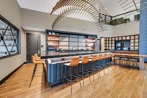 Une cuisine moderne dotée d’un îlot central, de tabourets de bar et d’un plafond haut orné d’un luminaire original.