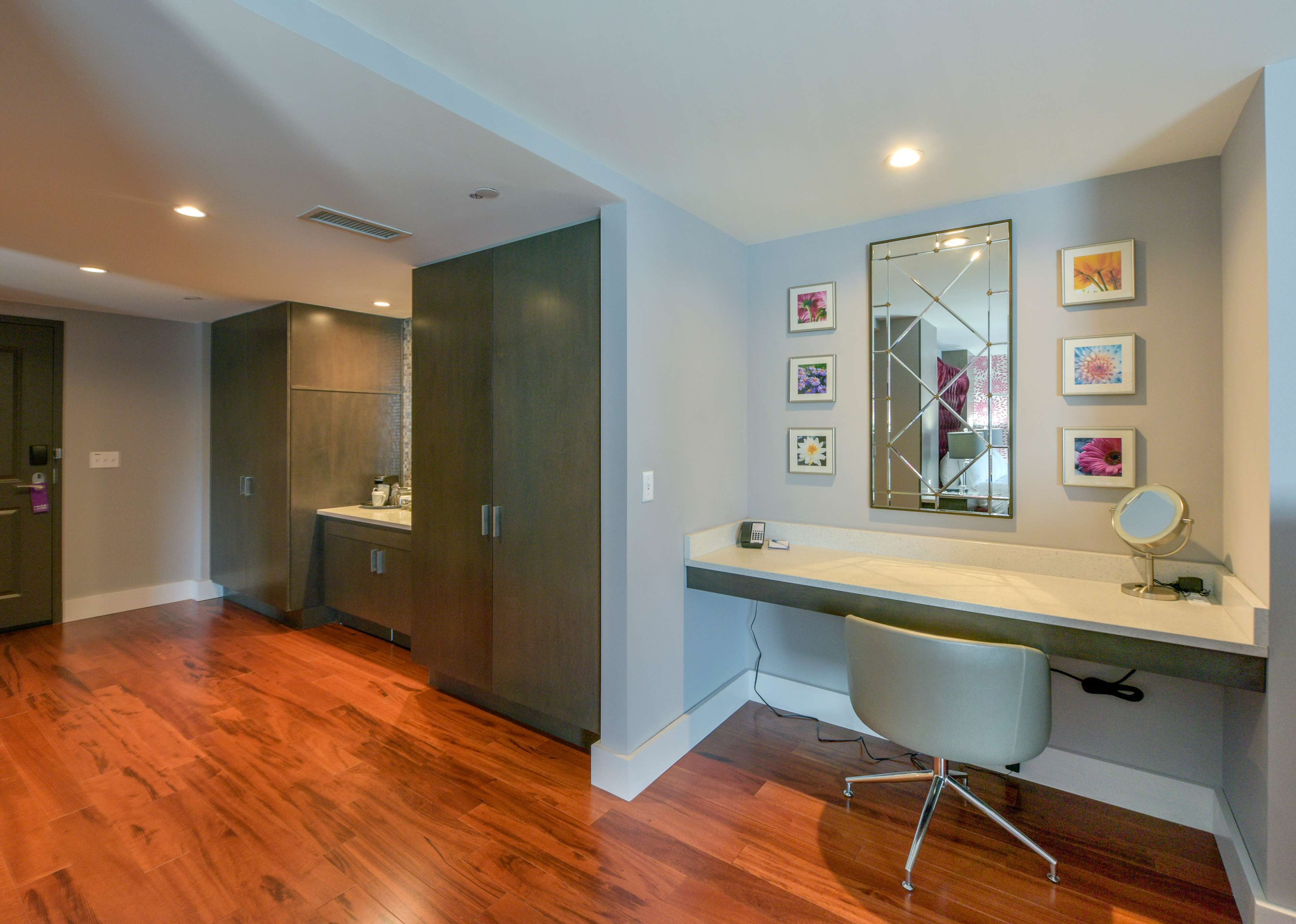 A modern bedroom with a large bed, a desk with a mirror, and a chair.