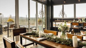 A restaurant with large windows offering a view of the countryside. Tables are set with candles and greenery. - DoubleTree by Hilton Asheville Downtown (Asheville)