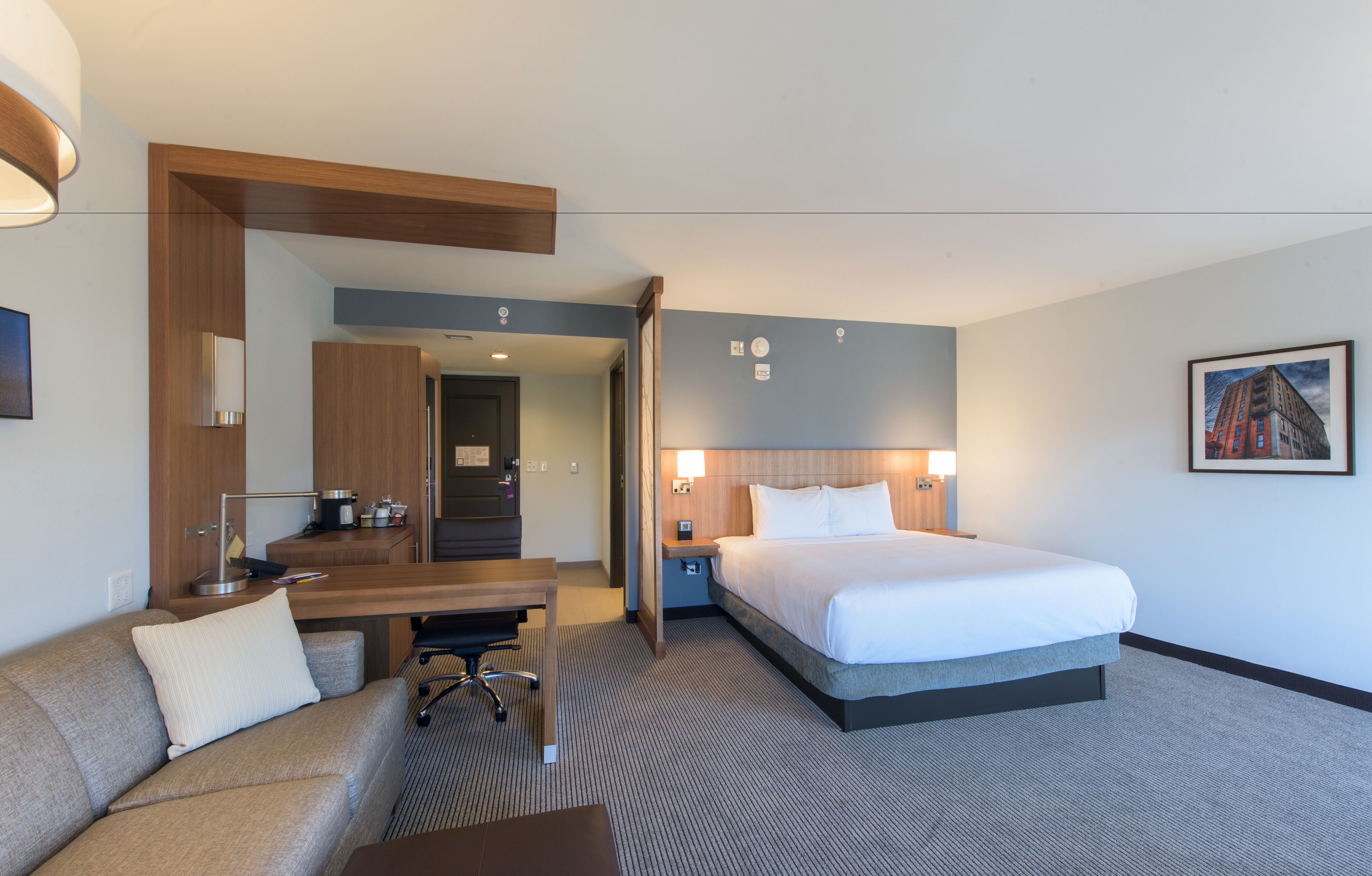 Ein Hotelzimmer mit Bett, Schreibtisch, Stuhl, Sofa und Badezimmer.